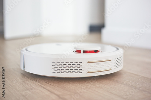 robotic vacuum cleaner on a laminated wooden floor Charging dock station Concept - Robot vacuum cleaner in the loft interior style close-up 