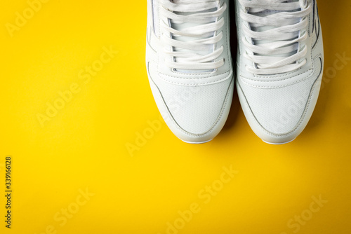 White sneakers on yellow background.
