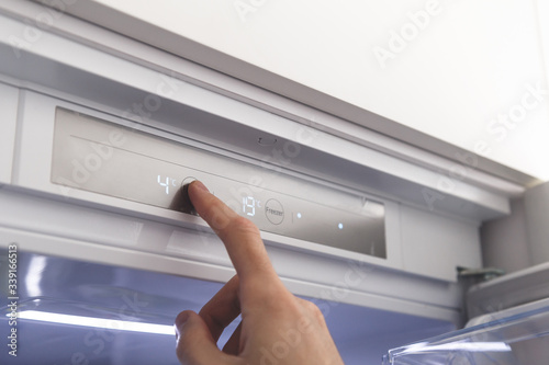 Hand sets temperature of refrigerator photo