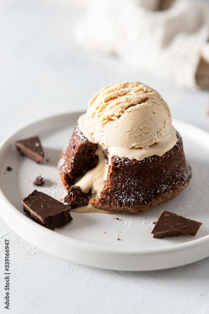 Warm Chocolate Lava Cake with Bite Taken Out of Molten Center and scoop of vanilla ice cream on white background. Restaurant, bakery, confectionery menu, recipe Warm Chocolate Lava Cake with Bite Taken Out of Molten Center and scoop of vanilla ice cream on white background. Restaurant, bakery, confectionery menu, recipe