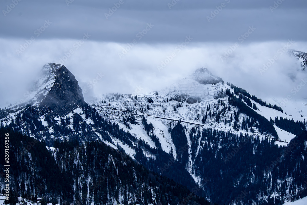 Snowcapped mountains surrounded by clouds in winter. Alpine mountains. Landscape scene.