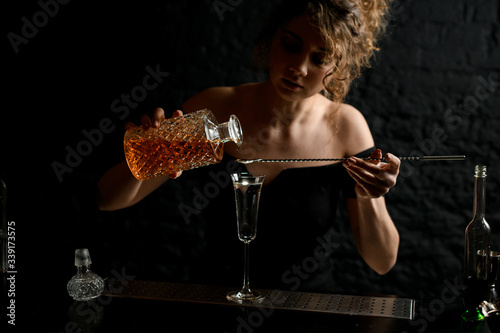 young attractive sexy girl at the bar pours drink into glass