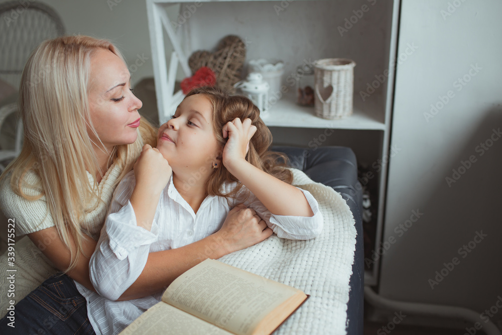 Mom and daughter read a book at home.