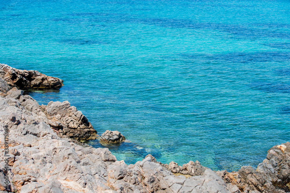 Closeup of vibrant blue waters and rocky coastline at Agia Dynami beach.
