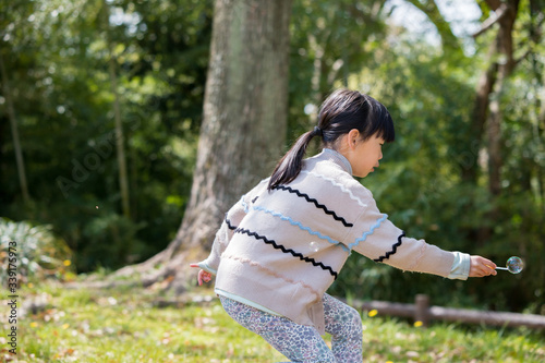 春の公園でシャボン玉を遊んでいる子供