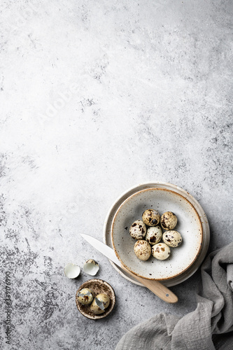  quail eggs in a ceramic bowl on a gray background, place for text.