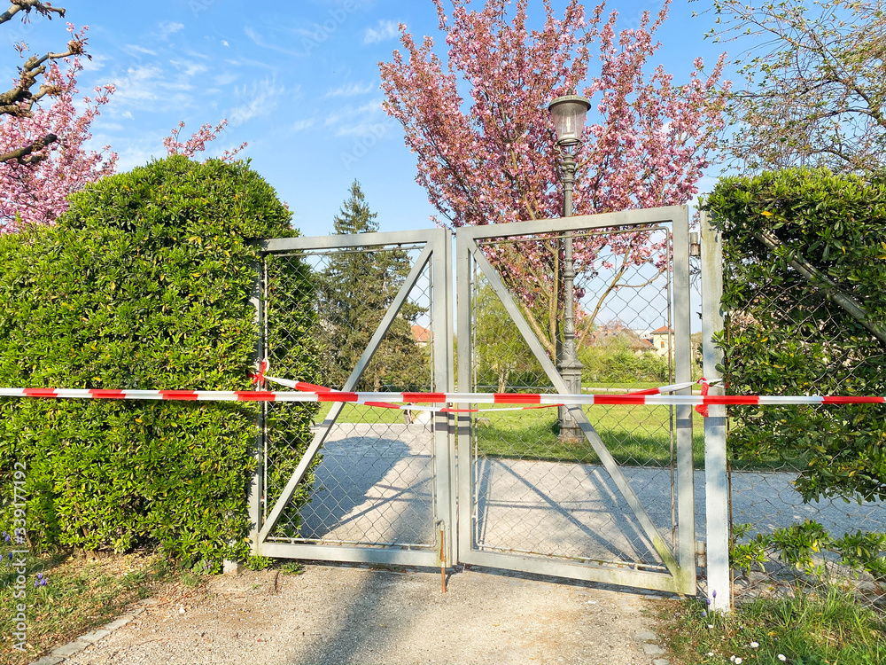 Gate to the park is closed and wrapped in alarm caution tape for global coronavirus quarantine. No people outdoor in Europe. Prevention of coronavirus COVID-19. Gate to the park is closed and wrapped in alarm caution tape for global coronavirus quarantine. No people outdoor in Europe. Prevention of coronavirus COVID-19.