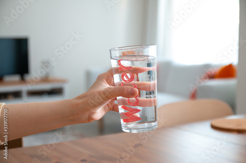 young beautiful lady drinking water in clean clear glass standing on table healthy