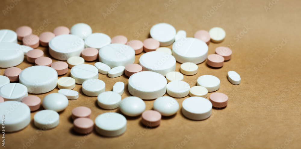 Heap of white pills, tablets, capsules on yellow orange background. Drug prescription for treatment medication health care concept wth copy space.