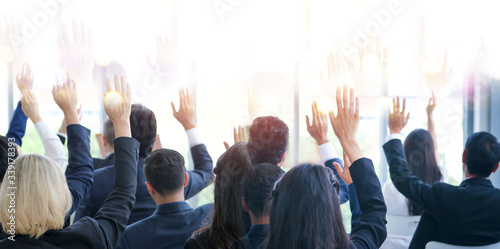 Banner image of back side of business people or employees sitting in conference room or seminar hall while show hand up agree or suggestion © torsakh