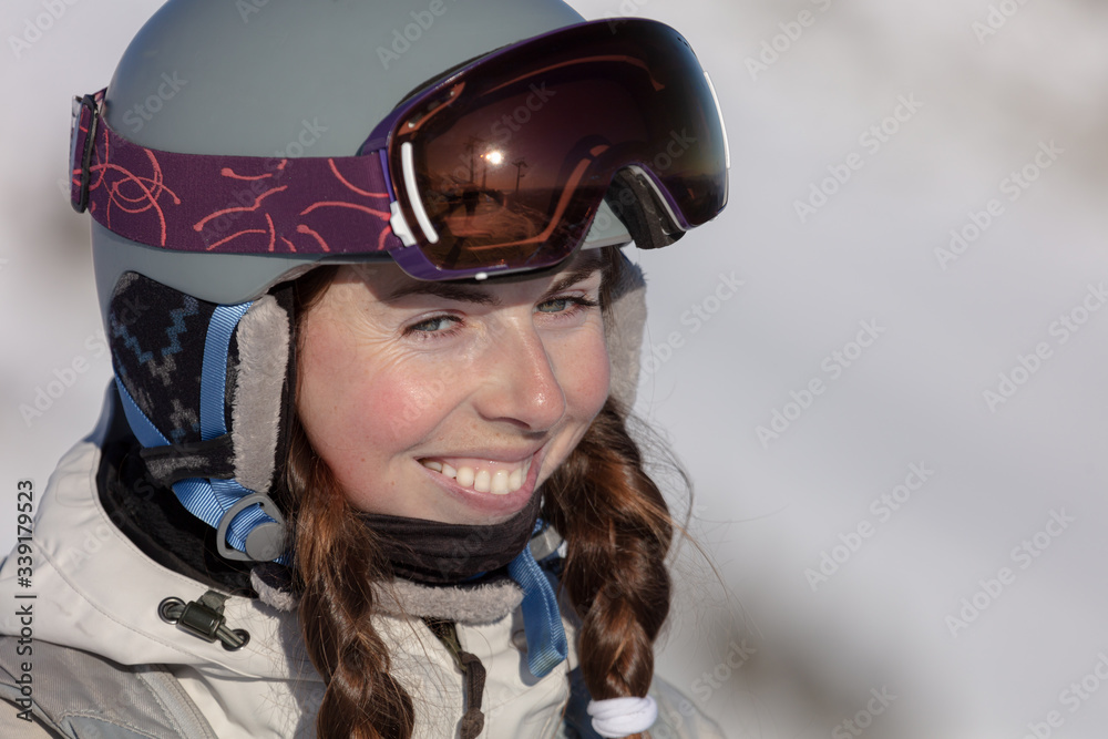 portrait of a happy girl in equipment at a ski resort. Young caucasian woman skier in European Alps. Winter sports and leasure activities. Pretty young woman with ski helmet. Ski winter sports concept