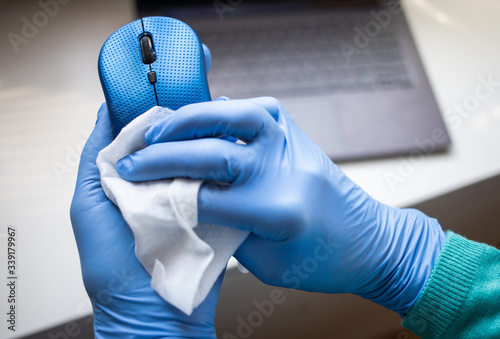 office sanitizing wipe wiping mouse and mousepad with disinfecting wipes. Coronavirus COVID-19 sanitize cleaning disinfection of work desk.