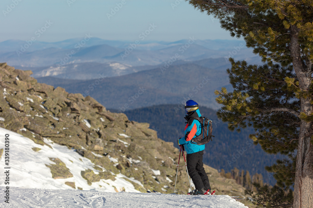 skier in a beautiful valley with a large cedar on the ski tour program. ski freeride, downhill in sunny day. Heliboarding skiing. fun at ski resort. Ski winter sports concept