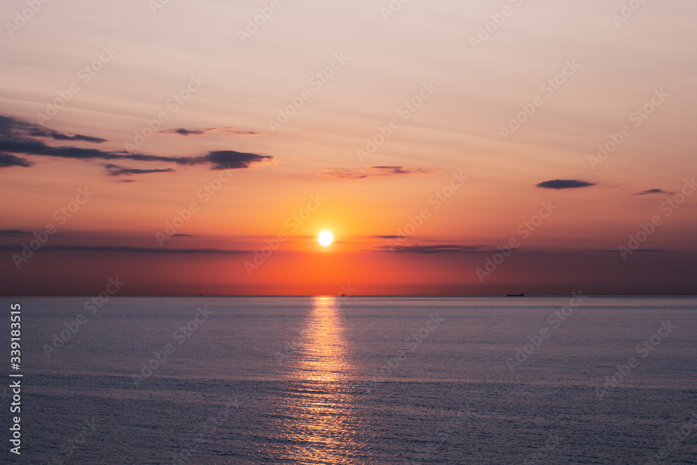 Sunset in the ocean with soft waves and red cloudy sky. Sea sunrise background. Landscape photography