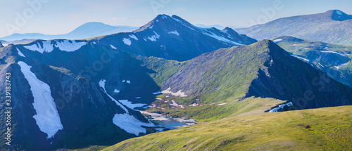 View from the top of the mountain valley in the evening. Snow, rocks and lake. Traveling in the mountains, trekking.