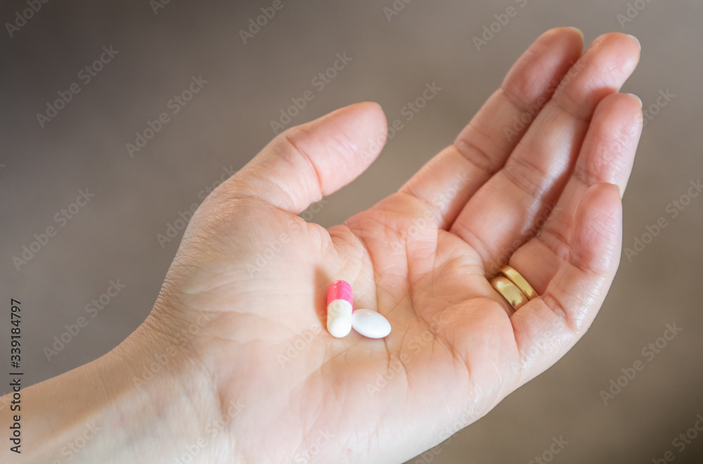 Hand holding different pills for medication of illness Hand holding different pills for medication of illness