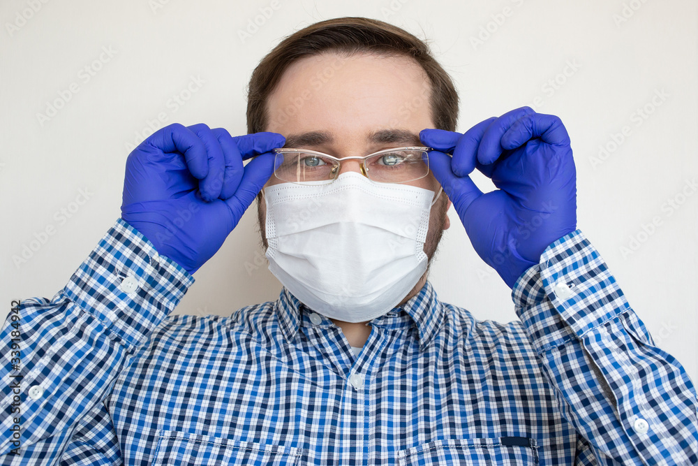 Man in a protective mask against coronavirus wearing eyeglasses isolated on white. Protection from the illness. Coronavirus, illness, infection, quarantine, medical mask Man in a protective mask against coronavirus wearing eyeglasses isolated on white. Protection from the illness. Coronavirus, illness, infection, quarantine, medical mask