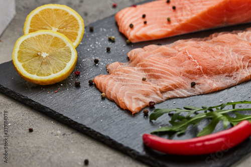 Fresh sliced salmon fillet with arugula, avocado and lemon on slate plate. Wild atlantic fish