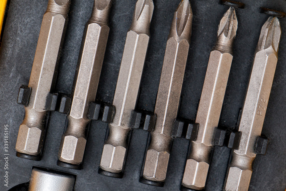Tool kit for home and repair. Screwdriver with nozzles of different types in a box on a spruce background. Tool kit for home and repair. Screwdriver with nozzles of different types in a box on a spruce background.