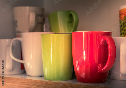 mugs and cups stored  in a cupboard on a shelf