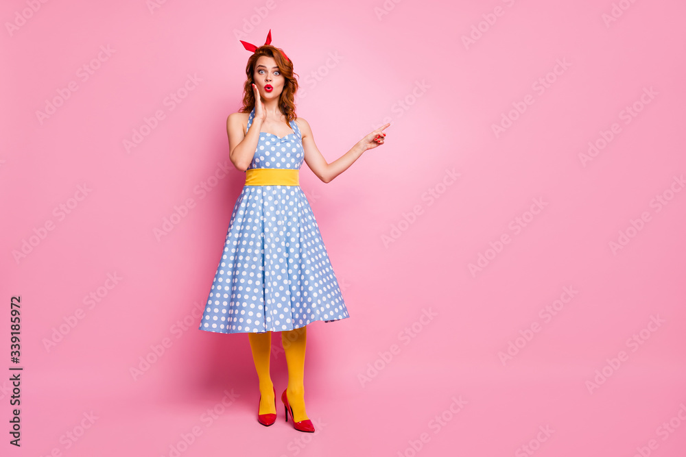 Full body photo of impressed lady look point index finger incredible discounts scream wow omg suggest pick tips wear blue polka-dot tights isolated over pink color background