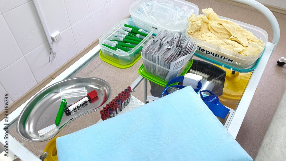 Medical table for blood sampling with test tubes and gloves in the treatment room of the hospital.