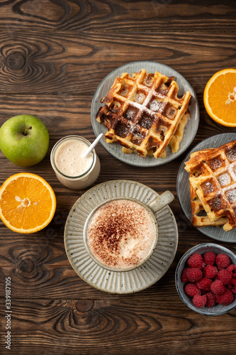 Belgian waffles, coffee, yogurt, fruits and berries on a wooden background, breakfast concept.