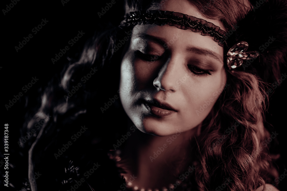 Portrait of vintage styled red haired woman dressed in Great Gatsby era flirting and posing on velours background. Roaring twenties, retro, party, fashion concept
