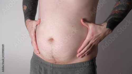 Hands of obese man touching his fat tummy. Close up of fat man shaking his stomach. Adult play with his fat belly. Overeating. Risk of diabetes. Weight loss or weight gain during quarantine. 
