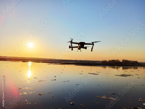 quadcopter flies over the river at sunset
