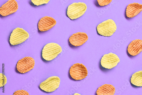 Potato chips colorful pattern on purple background. Vegan spinach, tomato, carrot snack chip. Crisps potato chips wallpaper, top view. Creative concept, fashionable trendy flat lay