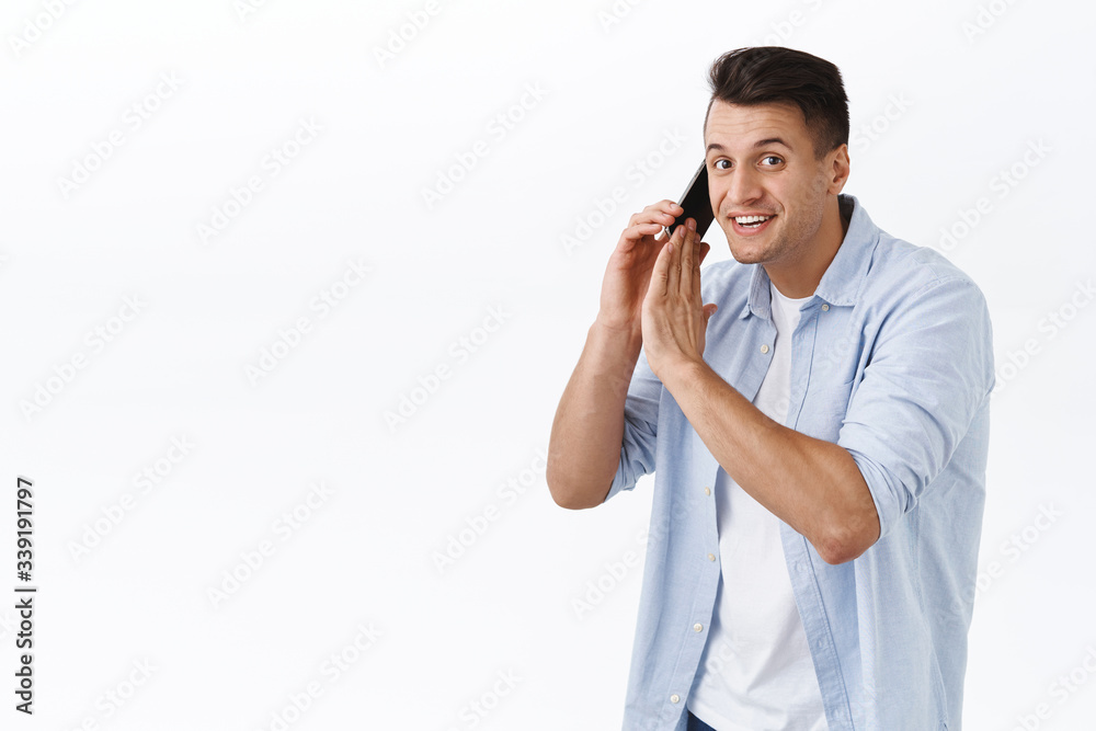 Sorry cant talk right now. Portrait of smiling handsome man busy talking on phone, hold mobile phone and cover dynamic to say something to you, having conversation, white background Sorry cant talk right now. Portrait of smiling handsome man busy talking on phone, hold mobile phone and cover dynamic to say something to you, having conversation, white background