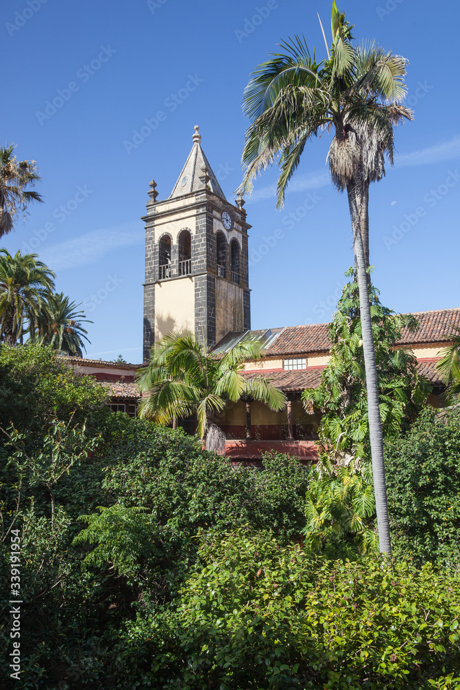 Old bell tower of the church of San Agustin, among palm trees in the historic town of La Laguna, Tenerife, Canary Islands, Spain.