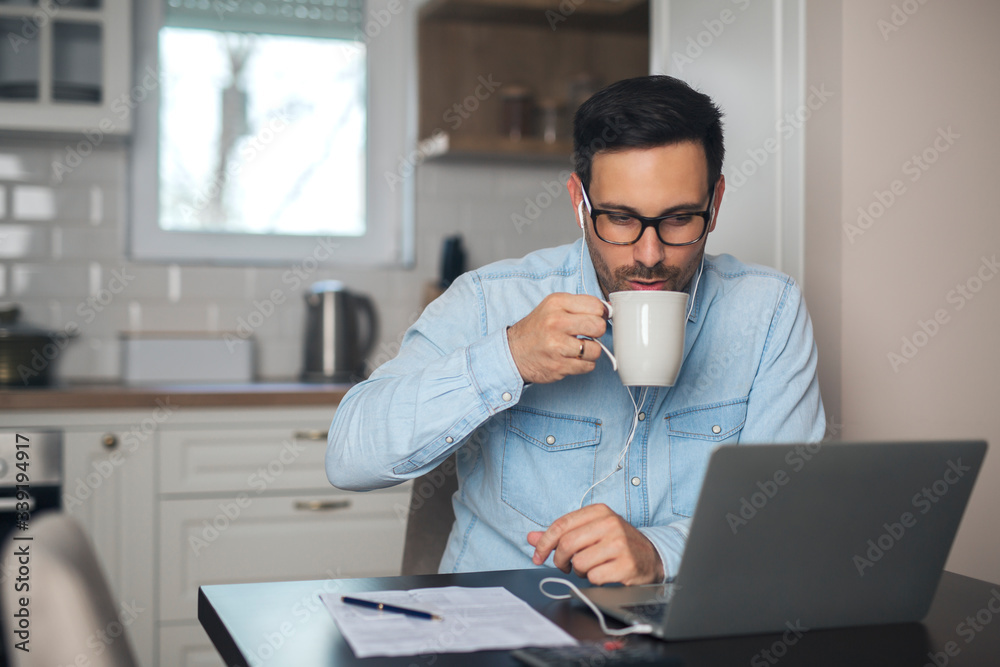 Man drinks coffee while having a video call on laptop. Man drinks coffee while having a video call on laptop.