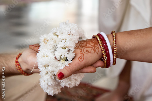 the bride and groom hold hands tied with a garland of white flowers. Beautiful traditional Indian wedding ceremony. Hindu wedding. indian engagement. Hindu the Vedic Yagya ceremony vivah Yajna