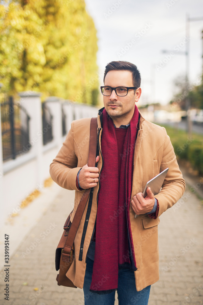 Businessman walking down the street holding tablet. Businessman walking down the street holding tablet.
