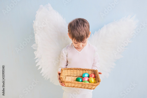 Angel boy in white with wing.Easter eggs