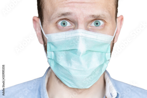 close-up of a male face in a medical mask with fear in his eyes on a white background