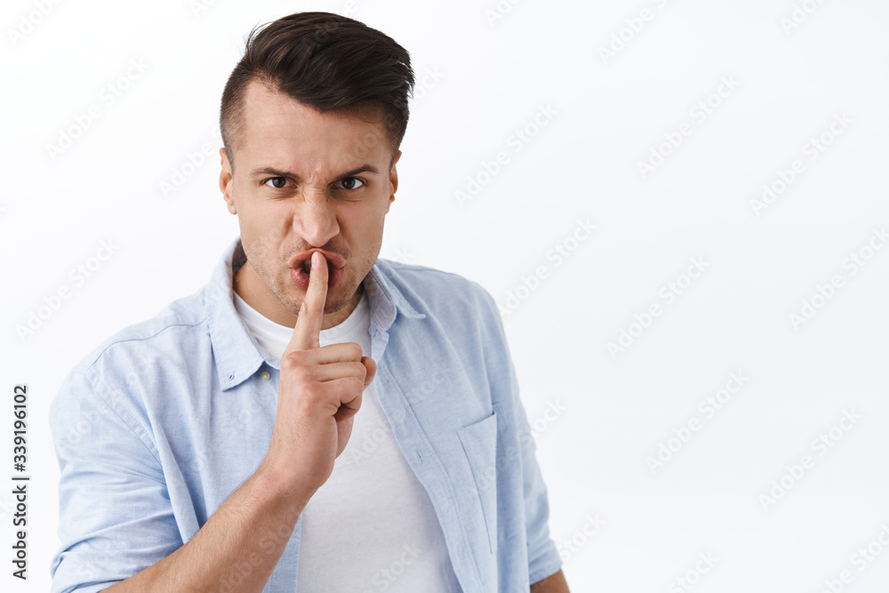 Portrait of angry, sick and tired man threaten person to shut up, shushing with annoyed face, press index finger to lips, demand silence, tell be quiet, standing white background irritated Portrait of angry, sick and tired man threaten person to shut up, shushing with annoyed face, press index finger to lips, demand silence, tell be quiet, standing white background irritated
