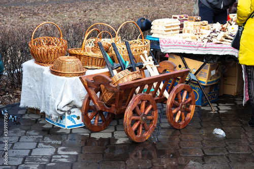 BOBRUISK, BELARUS 10.03.2019: Sale of wood products handmade. Wooden wagon with wicker baskets on it, traditional photo