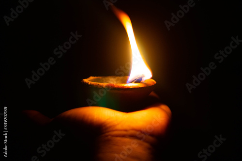 Lit diya or clay lamp on the palm of a person photo