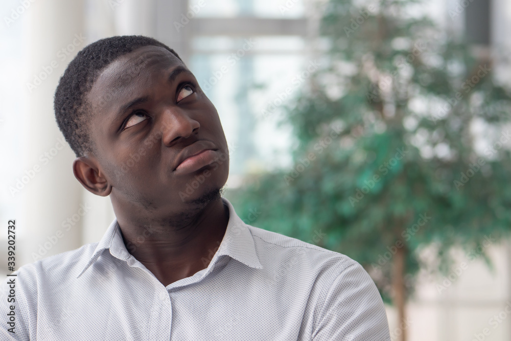 Upset African black man looking up; African black man looking with negative feeling, bad emotion, stress, problem Upset African black man looking up; African black man looking with negative feeling, bad emotion, stress, problem