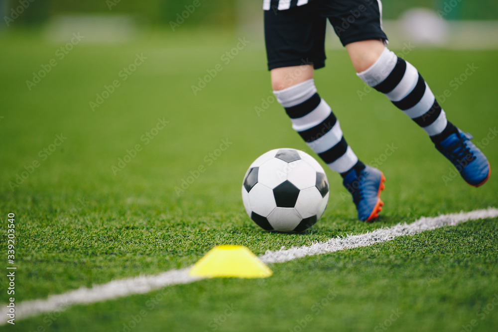 Detail soccer player kicking ball on pitch sideline. Soccer player on a game. Detail soccer background. Close up of legs and feet of footballer on green grass pitch