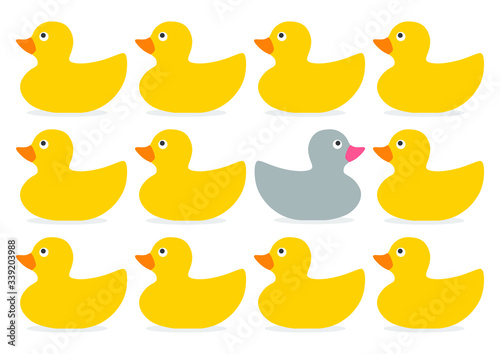 A non-conformist depiction of a grey rubber duck swimming against the flow of yellow rubber bath ducks