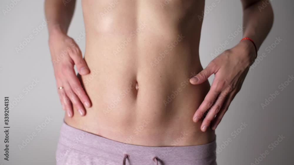 Girl touches her flat belly with her hands and retracts her stomach. White female's fit body and tan skin. Caucasian woman's flat stomach and arms. Weight Loss During Quarantine Girl touches her flat belly with her hands and retracts her stomach. White female's fit body and tan skin. Caucasian woman's flat stomach and arms. Weight Loss During Quarantine