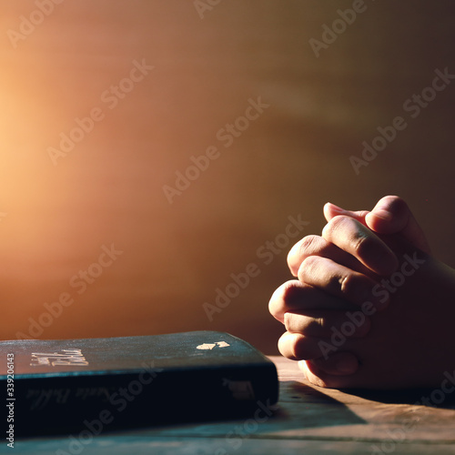 Hand Clasping and Bible on wooden table, praying to God for patients with coronavirus, copy space