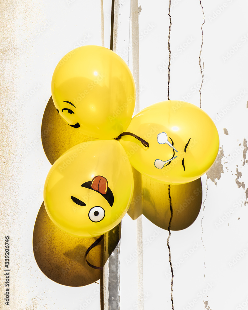 Fun, yellow emoji balloons bunched together in the sun for a street party in Senigallia, Le Marche, Italy