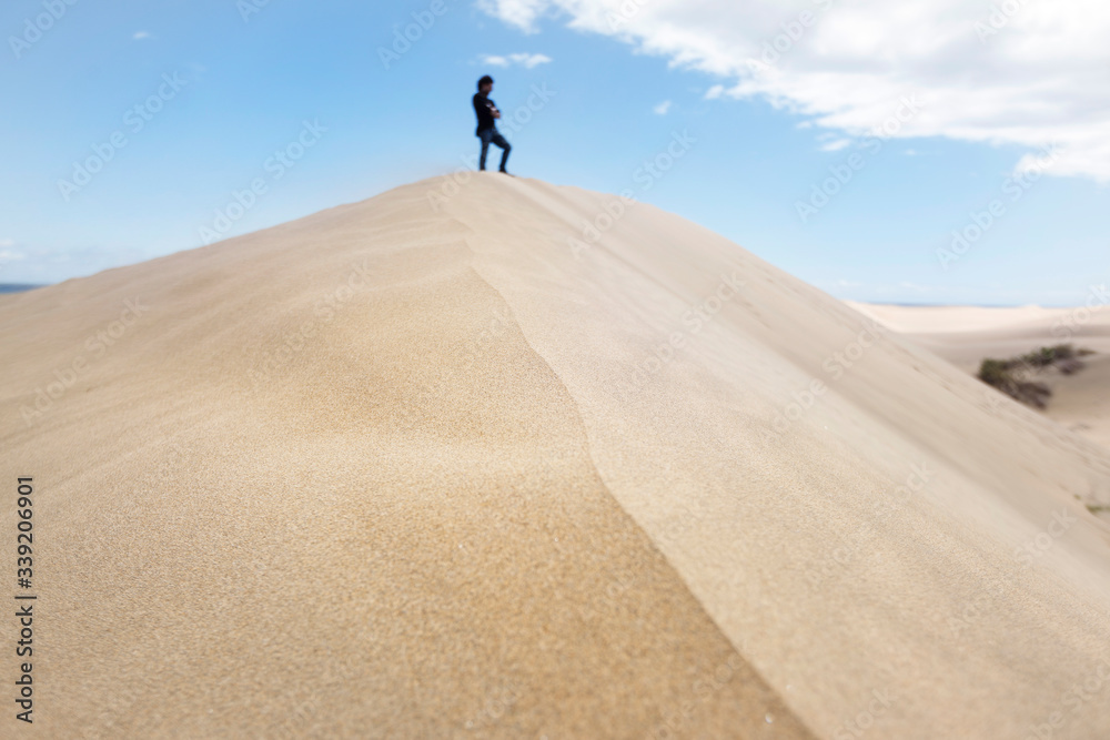 Panoramic view of huge dune in Maspalomas desert. New experiences traveling around the world. Unrecognizable man enjoying freedom. Travel and holidays concept. Canary Islands natural landscape.