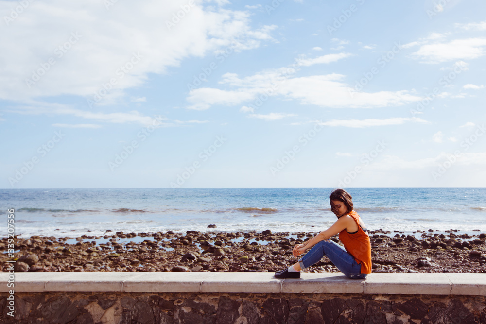 Isolated woman sit on the beach on holidays. Travel and holidays concept. Young woman enjoying summer vacations in the touristic destination Maspalomas. Tourism in spanish Canary islands.