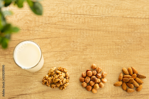 High angle view almond and milk in white bowl on  wooden textured background. Various vegan plant based milk and ingredients , top view, copy space. Dairy free milk substitute drink, healthy eating